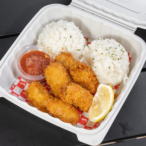 Crispy fried shrimp with white rice, a lemon wedge, and dipping sauce in a takeout container.