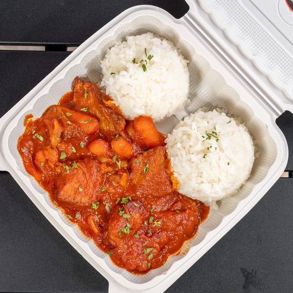 Chicken stew with carrots and two scoops of white rice in a takeout container.