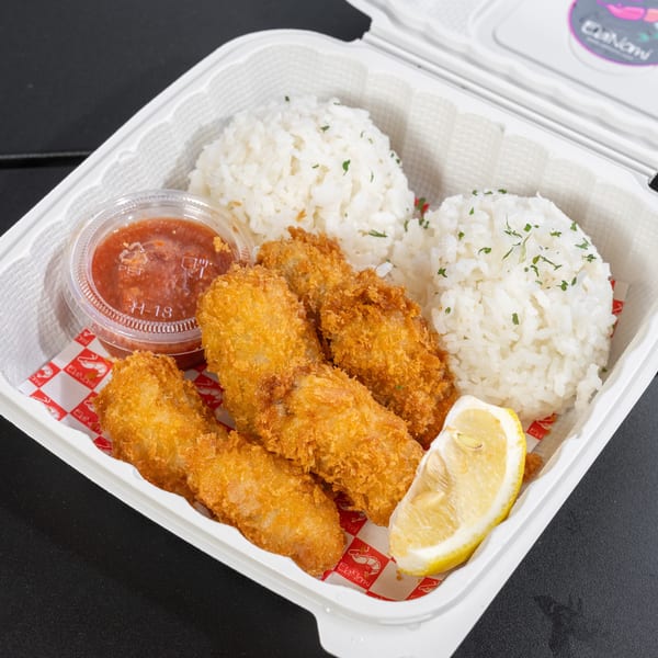 Fried shrimp, white rice, lemon wedge, and dipping sauce in a to-go container.