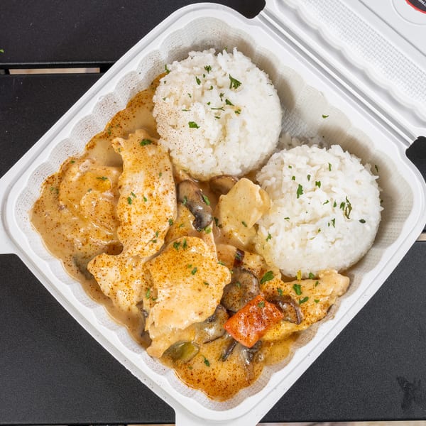 Creamy chicken and mushroom dish with two scoops of white rice in a takeout container.