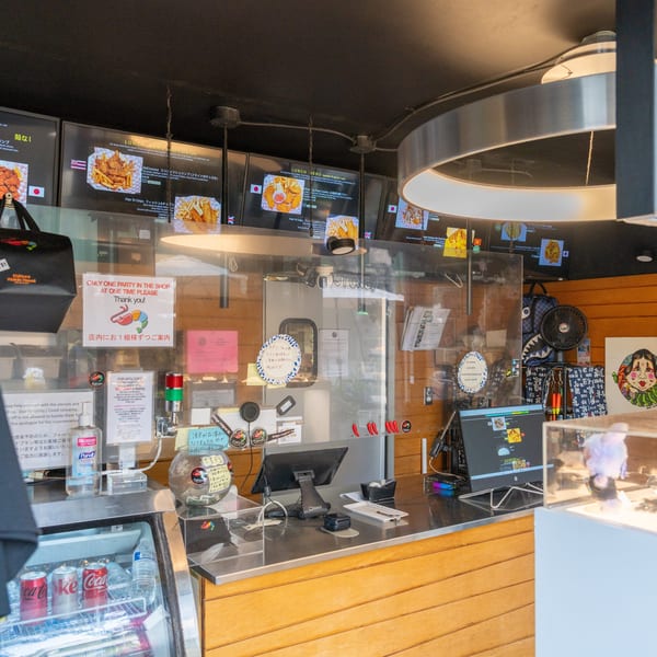 A restaurant counter with a clear barrier, menus, and various items, including a thermal bag.