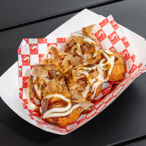 EbiNomi takoyaki with mayonnaise, sauce, and bonito flakes in a red and white checkered tray.